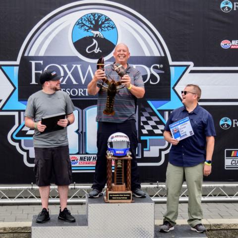 Billy Thomas (center) from WPKZ 105.3 FM/1280 AM in Fitchburg, Mass. won the fourth annual Media Racing Challenge at New Hampshire Motor Speedway Friday and was presented with a trophy, eight-pound live lobster and a $100 gift card to Makris Lobster and Steak House in Concord, N.H. Timmy G. (left) from The Wicked Fast Podcast on 105.7 WROR in Boston, Mass. came in second and Adam Drapcho (right) from the Laconia Daily Sun in Laconia, N.H. came in third. 