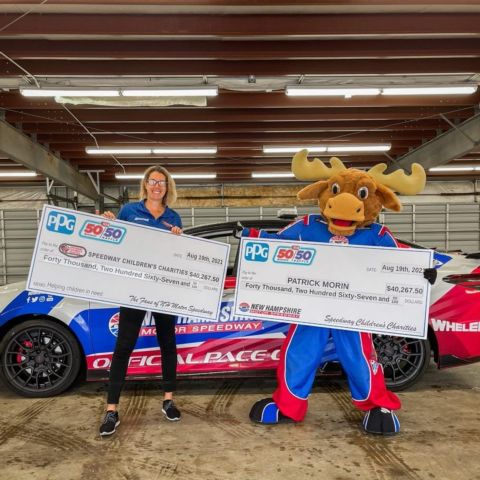Danielle Cyr, director of the New Hampshire Chapter of Speedway Children’s Charities and marketing for New Hampshire Motor Speedway (left) and Milo the Moose (right) show the winnings from the inaugural NASCAR weekend 50/50 Raffle Presented by PPG last year.